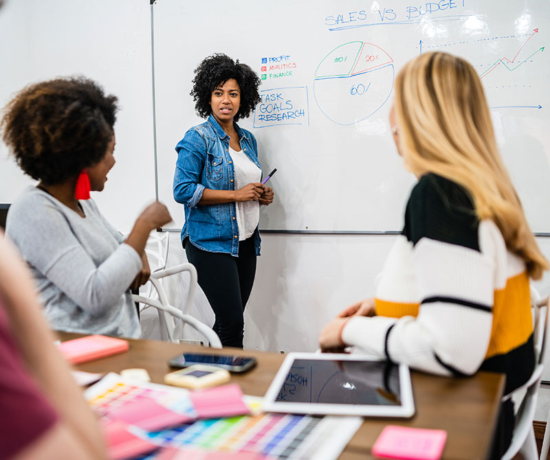 Black woman standing in front of white board talking